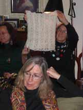 Eileen holds up Sage's knitted pygora circular head scarf.