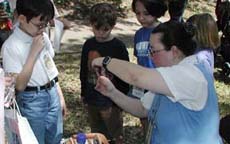 Connie Creed shows children how to use a drop spindle at Austin Science Fun Day.